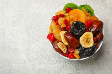 Mix of different dried fruits in bowl on grey table, top view. Space for text