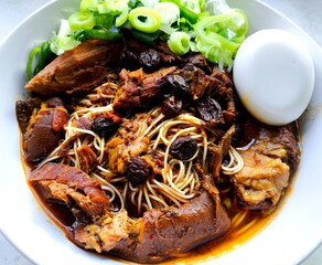 Yellow noodles with chopped steamed pork legs in bowl, in door Chiangmai Thailand.