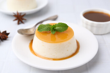 Tasty pudding with caramel sauce served on white tiled table, closeup