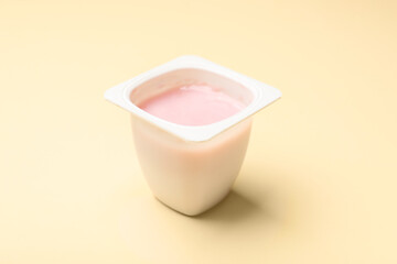 Delicious yogurt in plastic cup on beige background, closeup