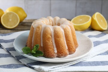 Tasty lemon cake with glaze and mint on wooden table, closeup