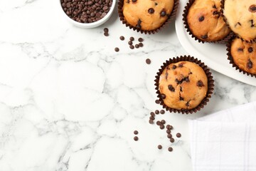 Delicious muffin with chocolate chips on white marble table, flat lay. Space for text