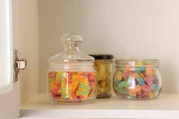 Tasty gummy candies in jars on shelf