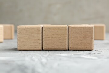 Blank wooden cubes on grey textured table, closeup