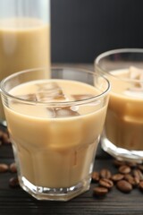 Coffee cream liqueur in glasses and beans on wooden table, closeup