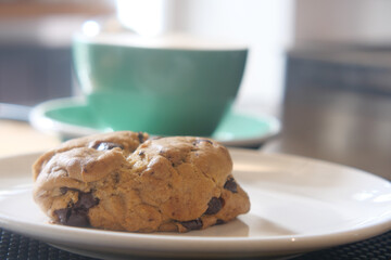 Warm chocolate chip cookie with a cup of coffee on a table