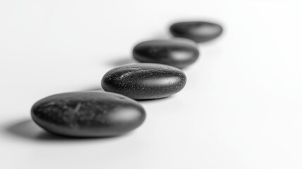 Arranged black river stones on pure white surface create calming and meditative atmosphere, perfect for wellness concepts