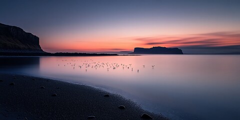 Fototapeta premium Serene sunrise over a calm bay with birds and cliffs.