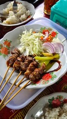 A plate of lamb satay with vegetables