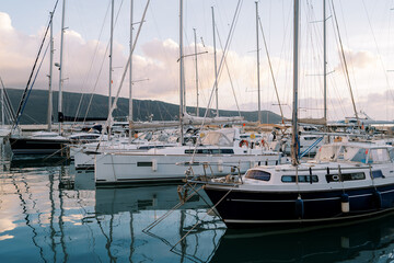 Marina with yachts at the foot of the mountains in the evening in sunset reflections