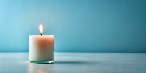 A single lit candle in a glass holder sits on a tranquil blue surface against a serene background
