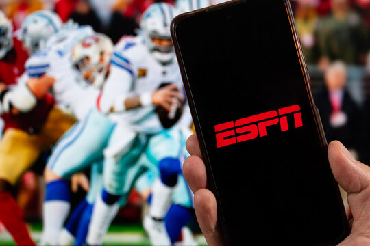 a male right hand with ESPN Sports tv channel logo inside a smartphone with american football blurred background