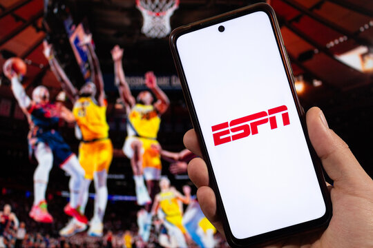 a male right hand with ESPN Sports tv channel logo inside a smartphone with basketball blurred background