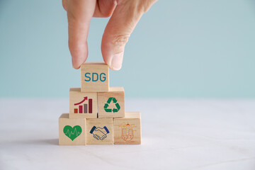 Hands holding wooden blocks with SDGs icons, Sustainable Development Goals concept
