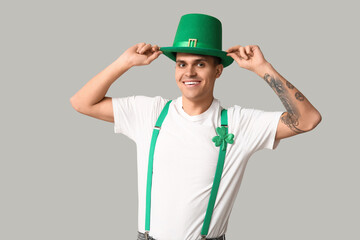 Happy tattooed young man in leprechaun's hat and with shamrock on light background. St. Patrick's Day