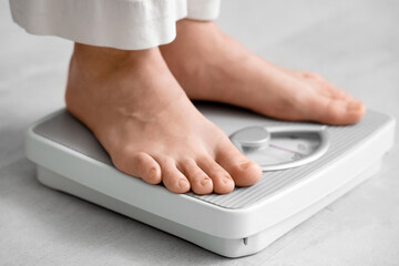 Fototapeta premium Young woman standing on scales at home, closeup. Weight loss concept