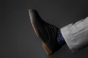 Leg of young man in elegant shoe on black background