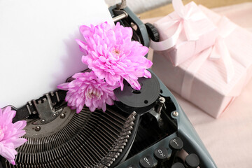Vintage typewriter with flowers and gift boxes on cloth, closeup