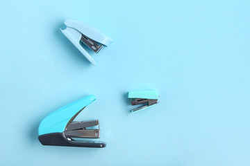 Blue staplers on color background