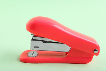 Red stapler on green background