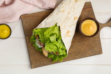 Tasty doner kebab and sauce on light table
