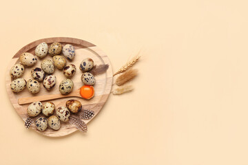 Wooden board with fresh quail eggs, feathers and wheat on beige background