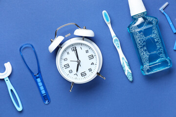 Alarm clock and set for oral hygiene on blue background