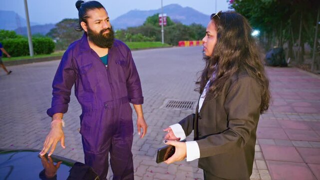Woman explaining mechanic about broken down car outdoor