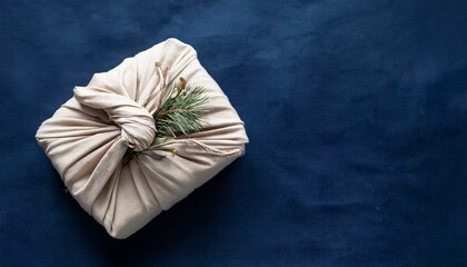 christmas new year present in ivory fabric on deep blue background zero waste gift wrapping traditional japanese furoshiki style