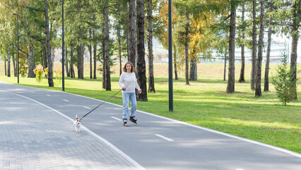 Obraz premium Caucasian woman roller skating with her jack russell terrier dog in park. 