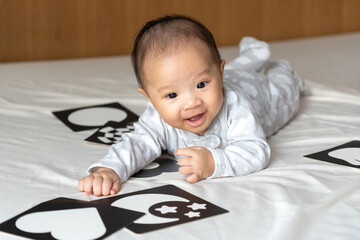 5 month old baby playing with picture cards on the bed in the morning.