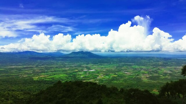 Aerial drone footage of a panoramic view of mountain ranges over comulus clouds.