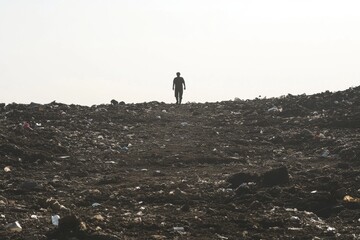 Solitary Figure Walking Across a Vast, Garbage-Strewn Landscape