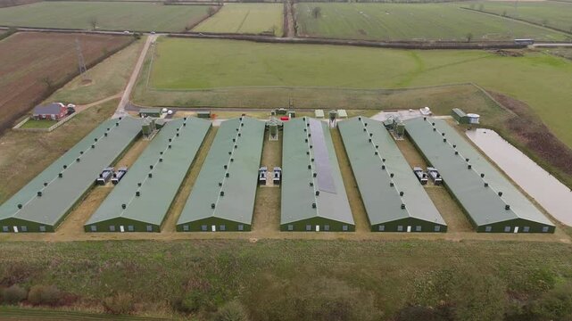Aerial explorative overview of farm buildings and warehouses chicken sheds green roof in England, UK agricultural livestock buildings 