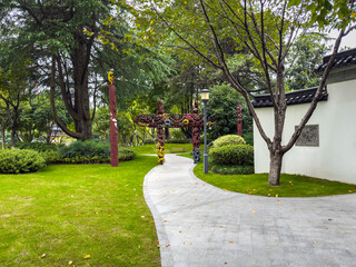 Tranquil Park Pathway Featuring Cultural Artwork and Lush Greenery