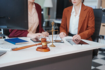 Two Caucasian women meet at a table, discussing legal matters. As lawyers, they advise clients on...
