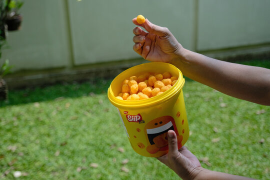 Hand holding a plastic bucket full of cheese chips which becomes very well liked by kids	