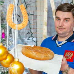 handsome young man holding freshly baked bread in his hands for New Year's holiday