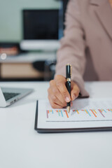 An Asian businesswoman accountant calculates invoices, taxes, interest, loans using a calculator,working online to guide clients through financial planning ensure a smooth loan process for success