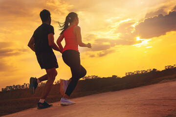Silhouette of young couple running together on road across the bridge. Couple, fit runners fitness...
