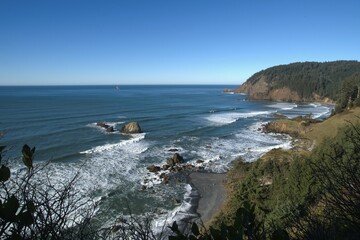 View of Oregon pacific ocean coastline including a shallow sandy beach covered with wave swells on a clear sunny.