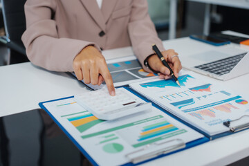 An Asian businesswoman accountant calculates invoices, taxes, interest, loans using a calculator,working online to guide clients through financial planning ensure a smooth loan process for success