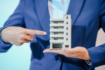 A female employee works at her desk in a real estate office, managing condo sales in the city. She...