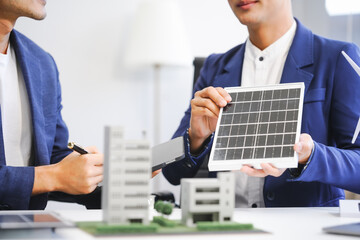 Two Asian businessmen meet at the table with wind power engineers to discuss renewable energy solutions. They exchange ideas on wind turbines, solar energy,simulations for sustainable development