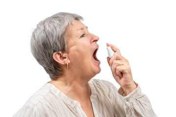 Senior woman spraying throat pain medicine into mouth isolated