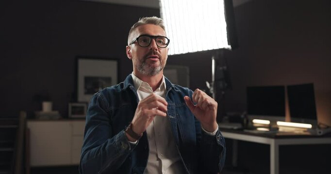 Talking, interview and man on set for recording with documentary, show or movie in studio. Filming, discussion and male journalist by lights for television public speaking with production equipment.