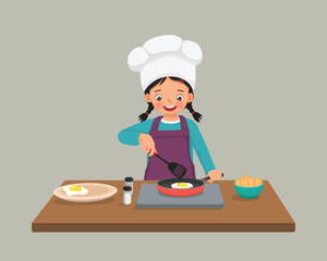 Cute little girl chef cooking delicious fried egg with frying pan in the kitchen

