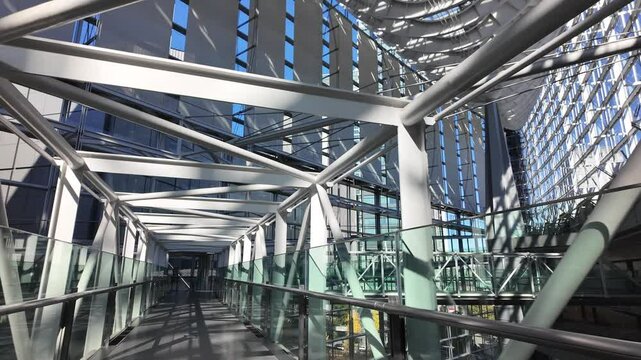 Futuristic walkway inside Tokyo International Forum building with metal beams and glass handrails