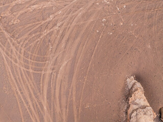 Fototapeta na wymiar Desert sand ground with many vehicle tire tracks