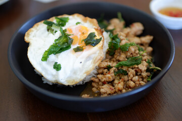 delicious Thai dish featuring stir fried minced pork with basil, served with rice and topped with fried egg, showcasing vibrant colors and textures